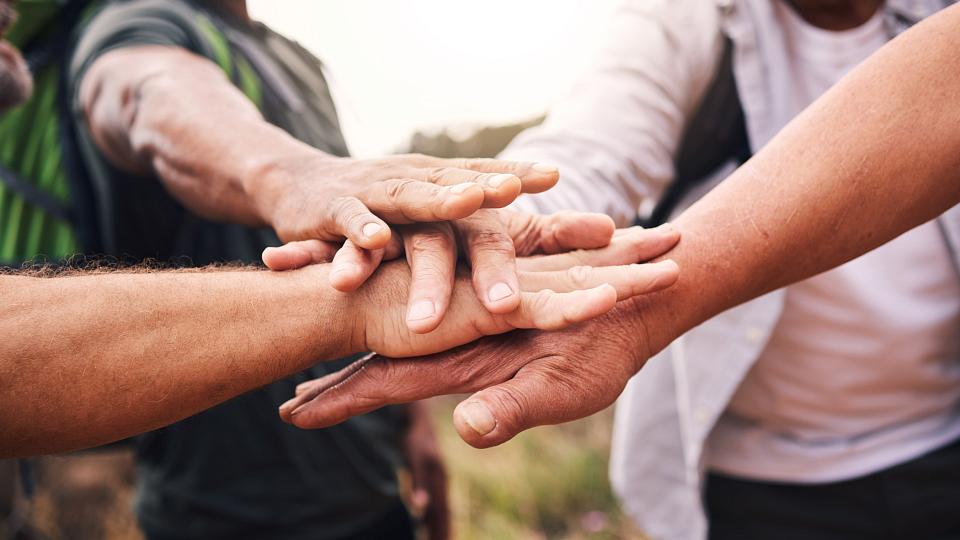 Group of men stacking their hands together to show support